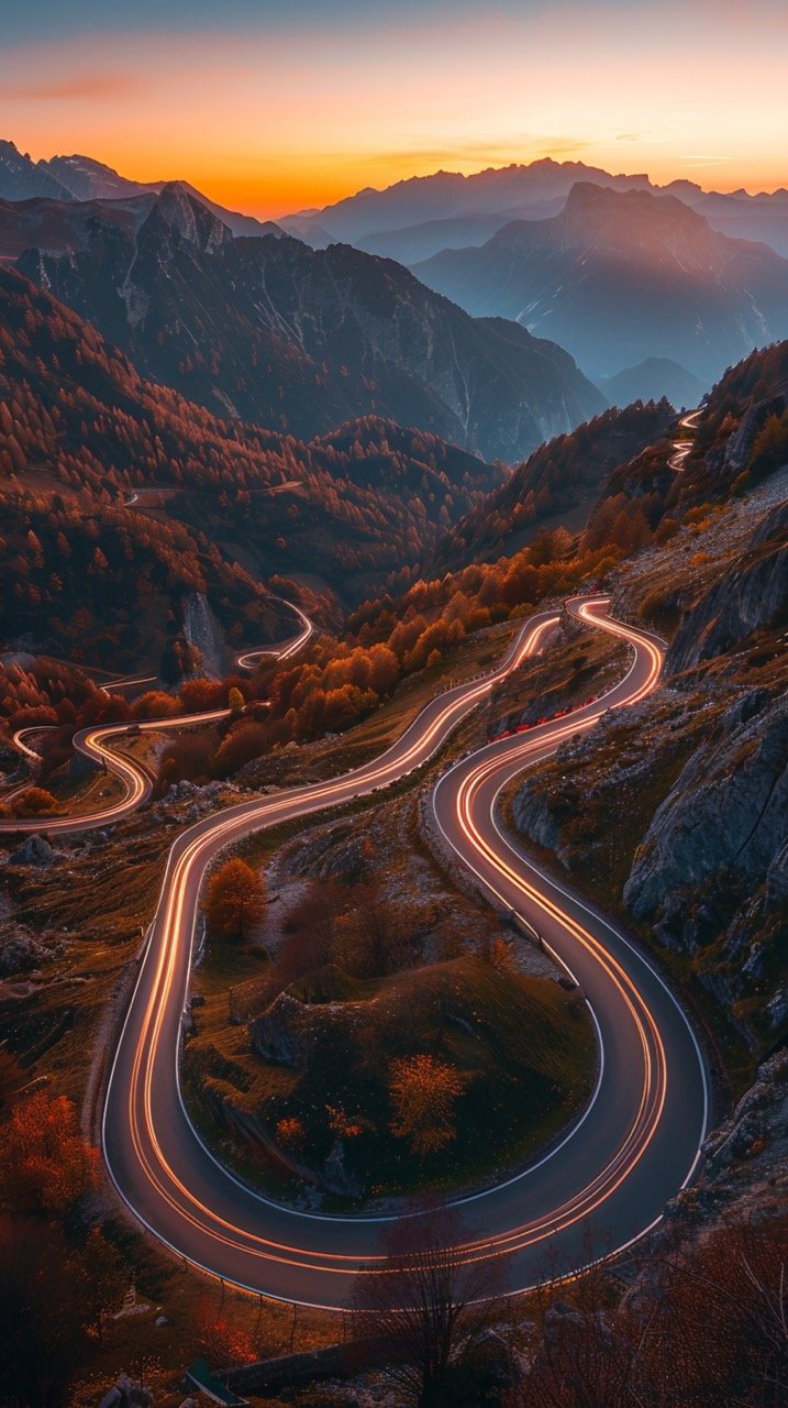 Red Sunset Over Twisty Mountain Road with Light Trails in Autumn – Aerial Perspective