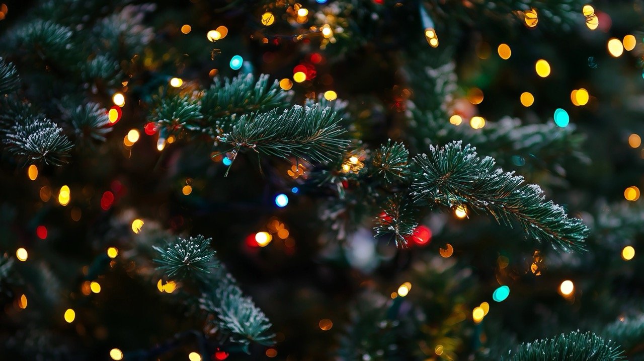 Close-up of glowing Christmas tree with garlands of lights, creating a festive holiday background for New Year celebrations.